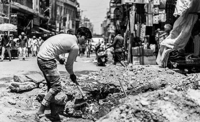 インドの路上で穴を掘る工事の青年
